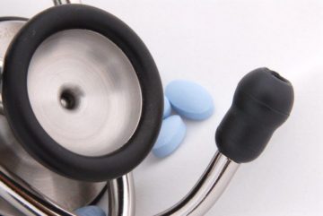 A close up image of a stethoscope with pills in the background